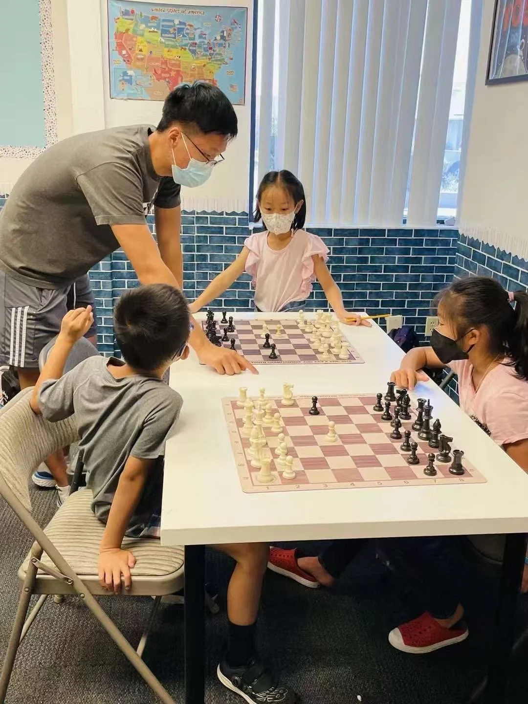 Students playing chess with teacher